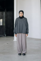A person wearing an oversized sweater in dark grey color by Swifter, paired with a long skirt.