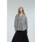 Woman wearing a checkered coat by Yestoday over a white shirt with a black skirt on a light gray background