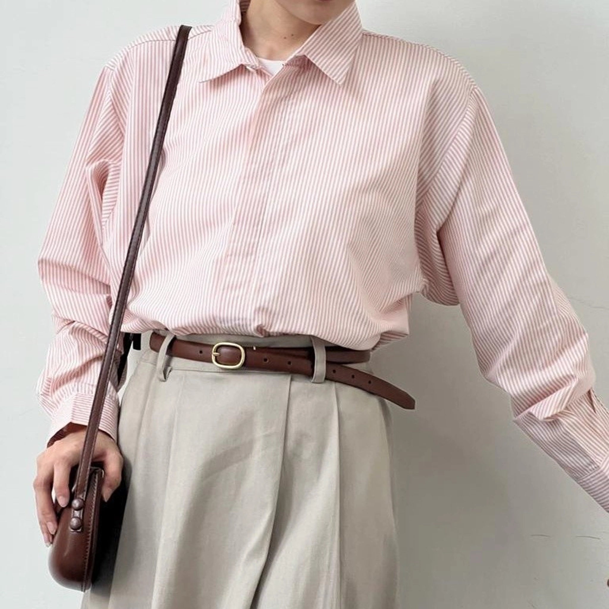 A person wearing a striped button-up shirt from BWBYAZ in pink and white, with the shirt's collar visible.