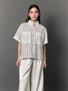 Woman wearing a striped shirt with lace details by Studio Tui against a gray background