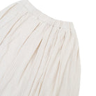 Close-up of a textured cream-colored textured balloon skirt by Yestoday, showing the pleated waistband and fine woven texture against a white background.