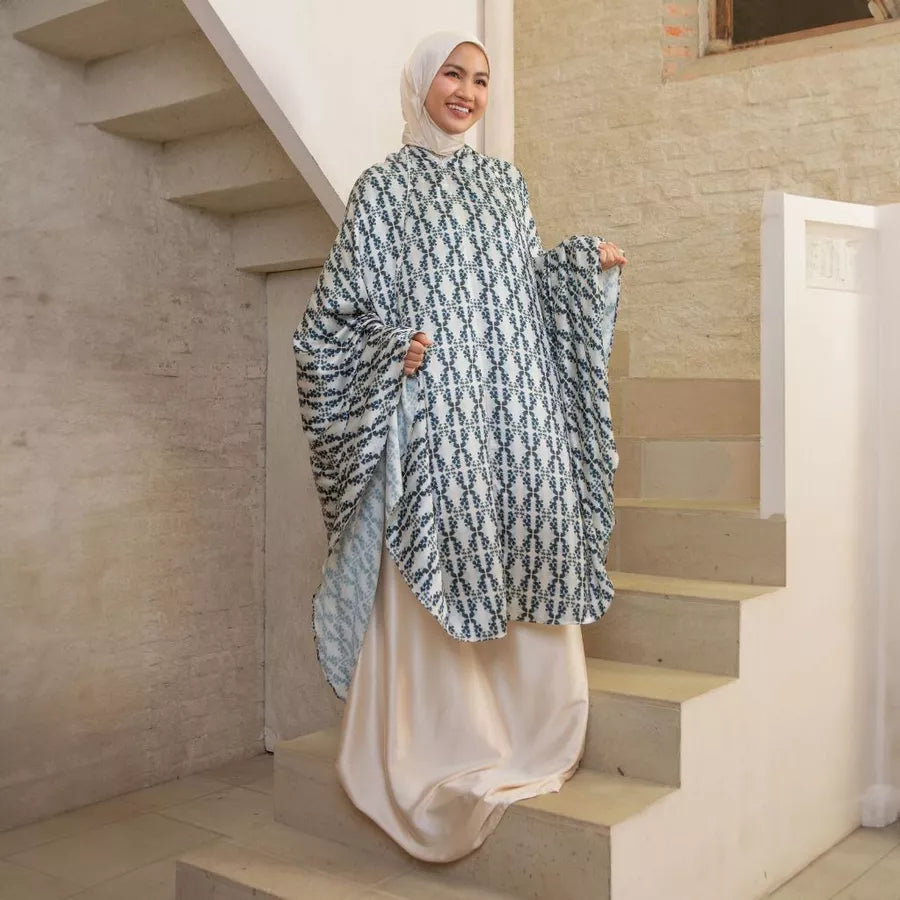 Woman wearing a patterned cream-colored prayer set by Lozy Hijab on a staircase