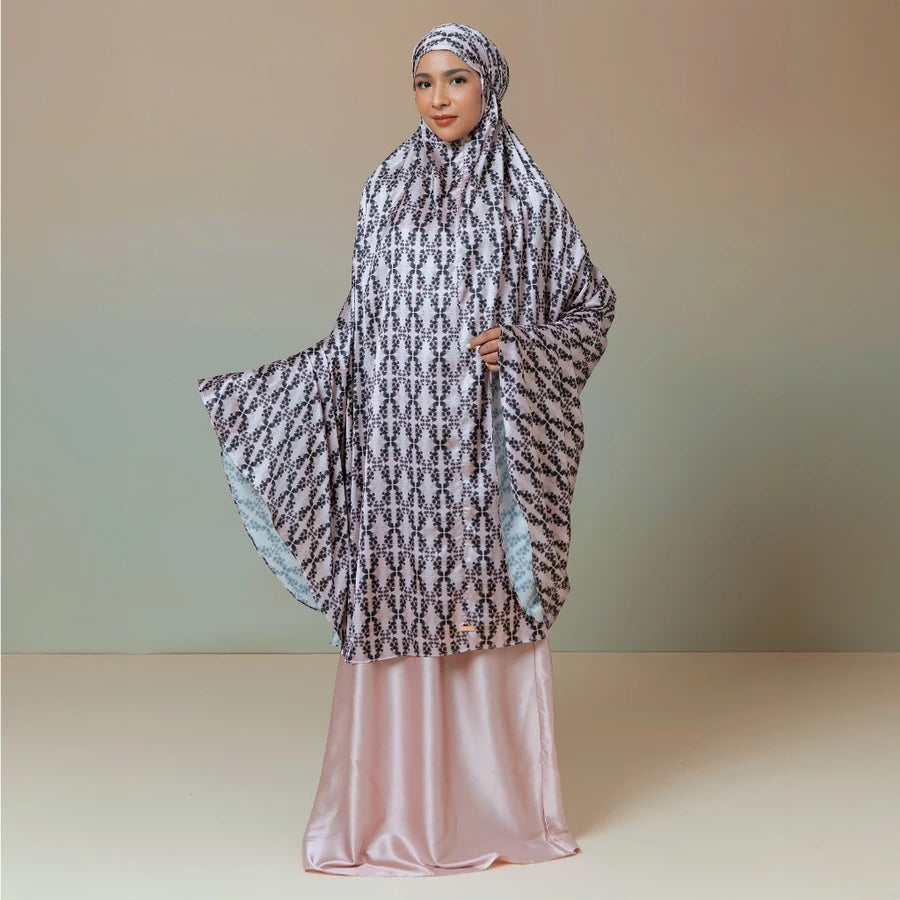 Woman wearing a patterned rose-colored prayer set by Lozy Hijab against a plain background