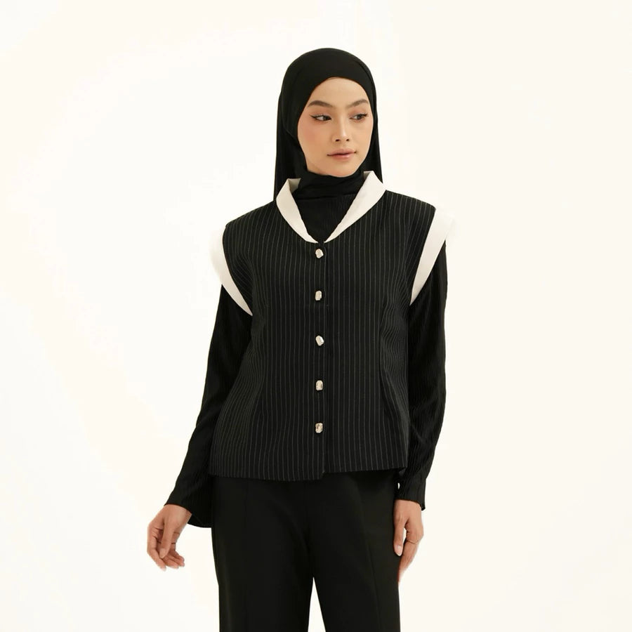 Person wearing a black vest with white accents by Tunique over black shirt on a white background