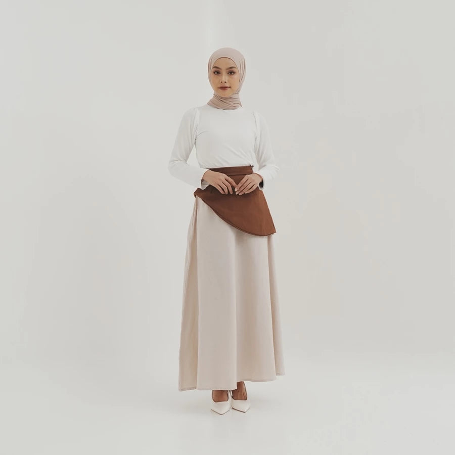 Woman wearing a white top and beige skirt by Tunique with a brown accents on a white background
