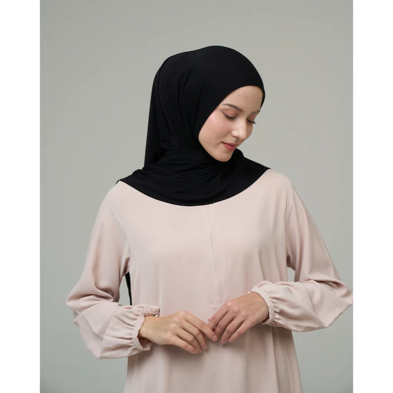 Woman wearing a black hijab by Inanna and light pink top on a gray background
