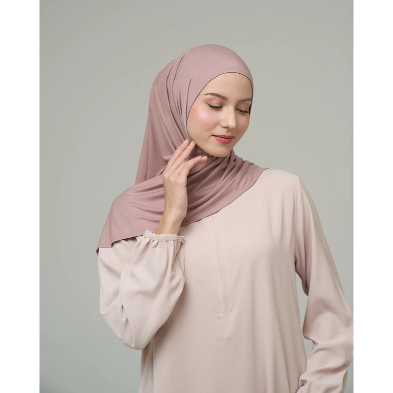 Woman wearing a pink hijab by Inanna and beige top against a gray background