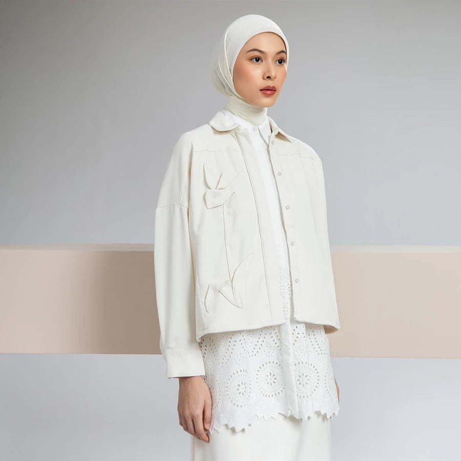 Woman wearing a cream-colored outer jacket by Hijabchic with a hijab against a neutral background