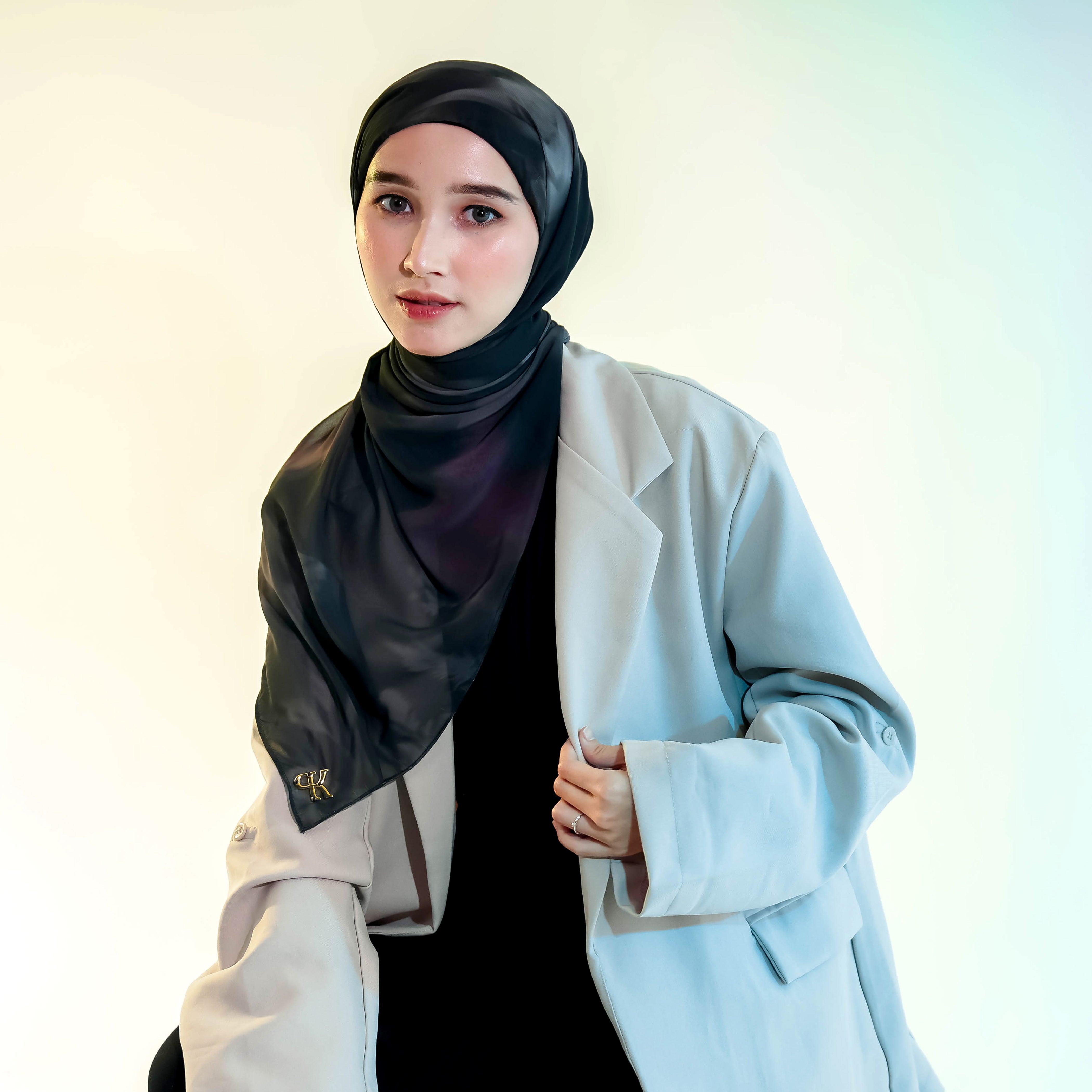 Woman wearing a black pashmina hijab by Puru Kambera and light blue blazer against a white background