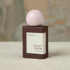 Perfume bottle labeled 'Velvet Moon' by hijabchic on a textured surface with a blurred background.