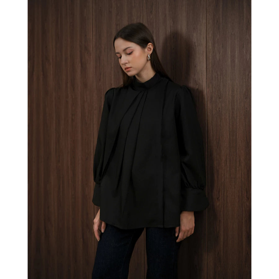 Woman wearing a black blouse by Kasa Heritage against a wooden paneled wall