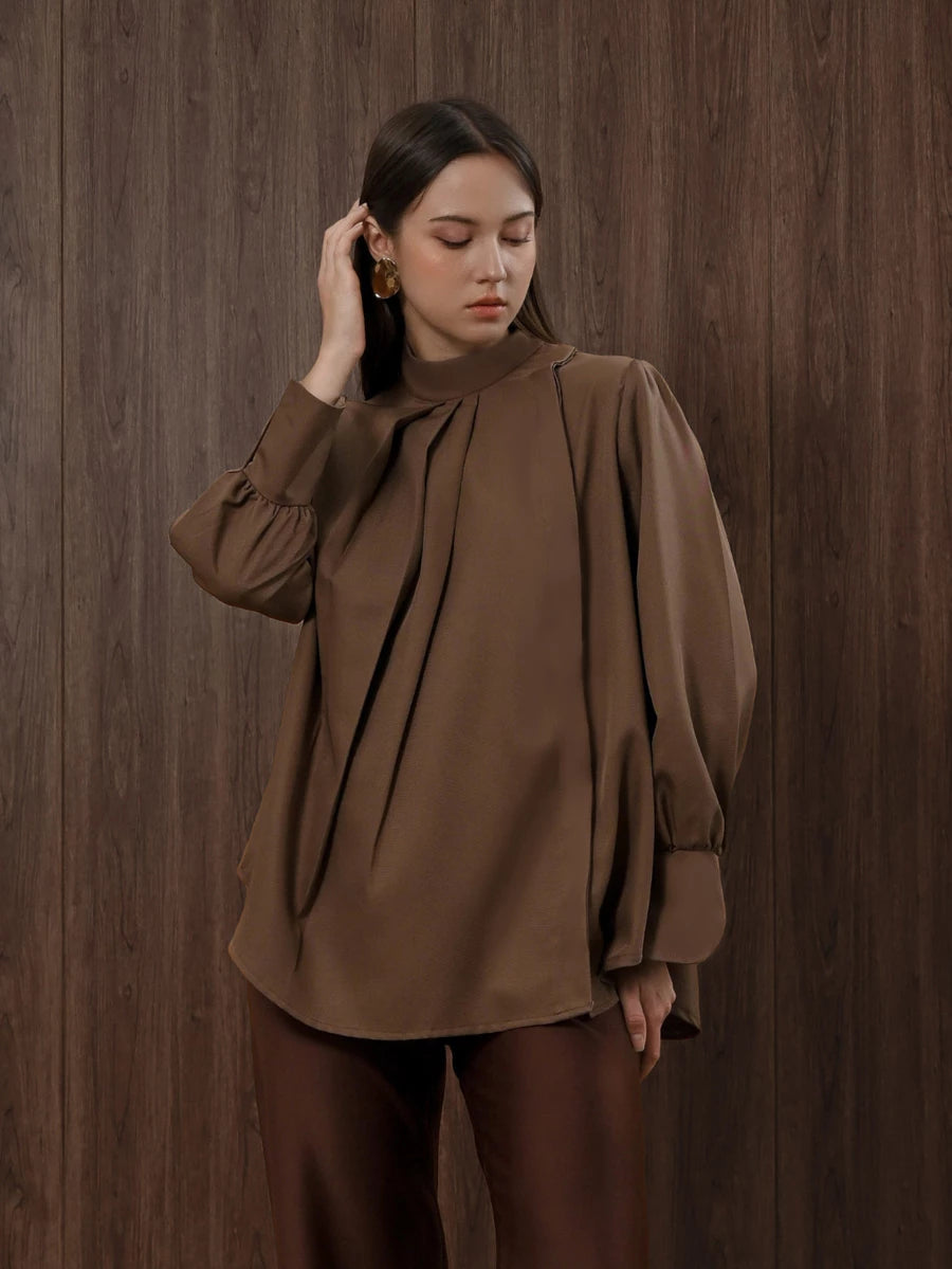 Woman wearing a brown blouse by Kasa Heritage against a wooden background