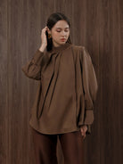 Woman wearing a brown blouse by Kasa Heritage against a wooden background
