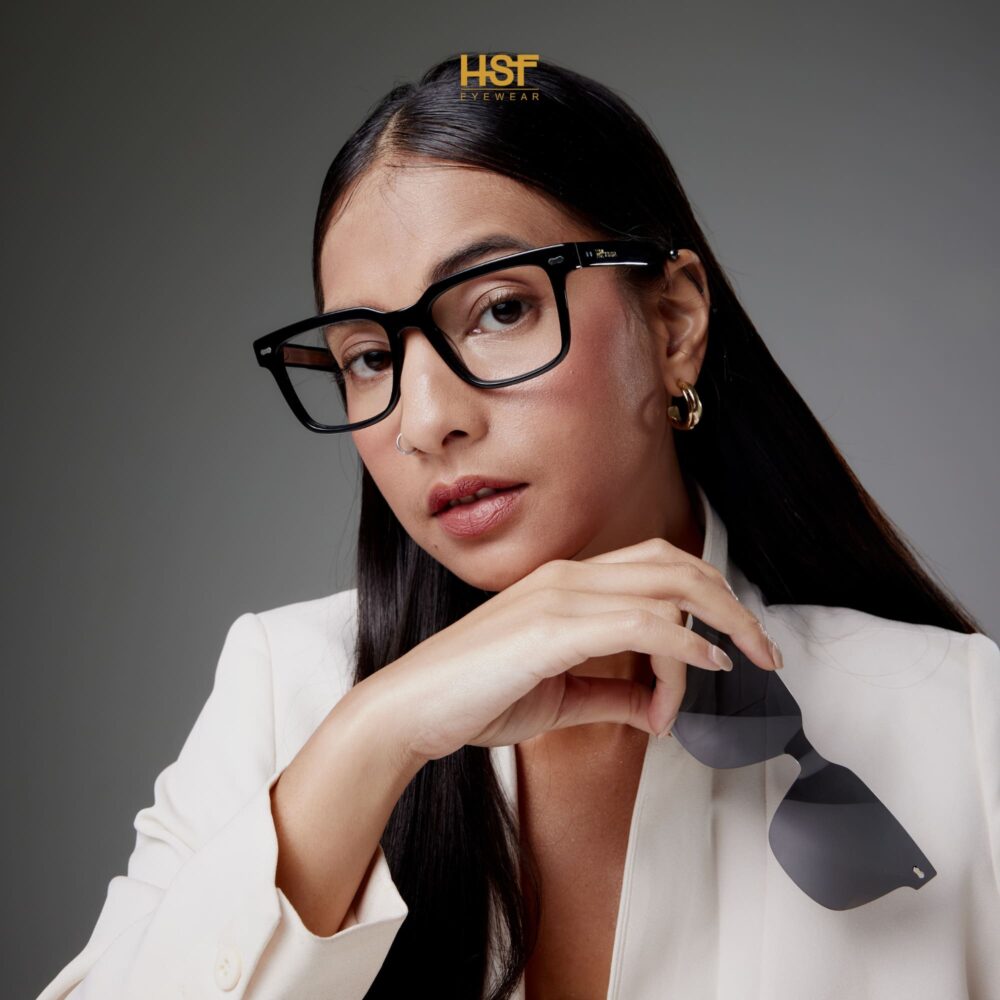 Woman wearing glasses with a gray background, featuring the HSF Eyewear logo.