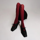 Red tights worn with black flat shoes by Cekhas on a white background
