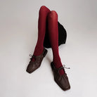 Red tights worn with brown flat shoes by Cekhas on a white background