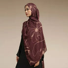 Woman wearing a maroon hijab with floral patterns by Lozy Hijab on a beige background