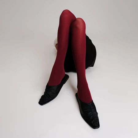 Red tights and black Vonee Mules flat shoes by Cekhas on a white background