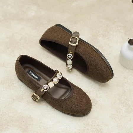 Dark brown flat shoes by Dianable with decorative straps on a textured surface