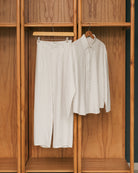 Broken white striped shirt and pants from Atala Scarves hanging on a wooden wardrobe.