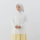 Person wearing a white shirt from Atala Scarves with a yellow skirt on a plain background