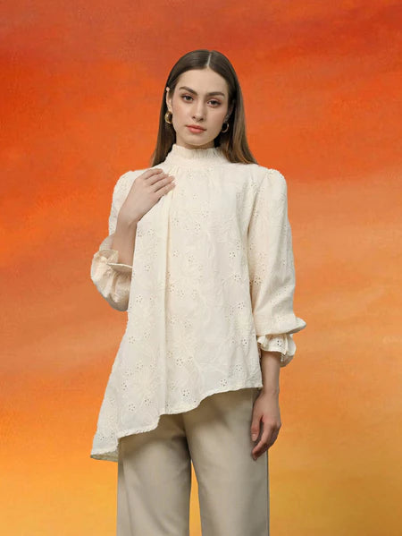Woman wearing a ivory-colored blouse with ruffled sleeves by Kasa Heritage against an orange gradient background