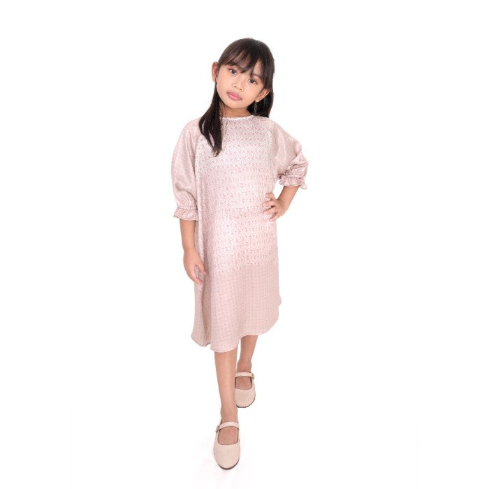 A girl in a pink midi-length tunic with long sleeves, standing against a plain background.