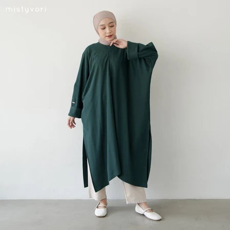 Person wearing a dark green long-sleeve abaya by Mistyvori and light-colored pants against a plain background
