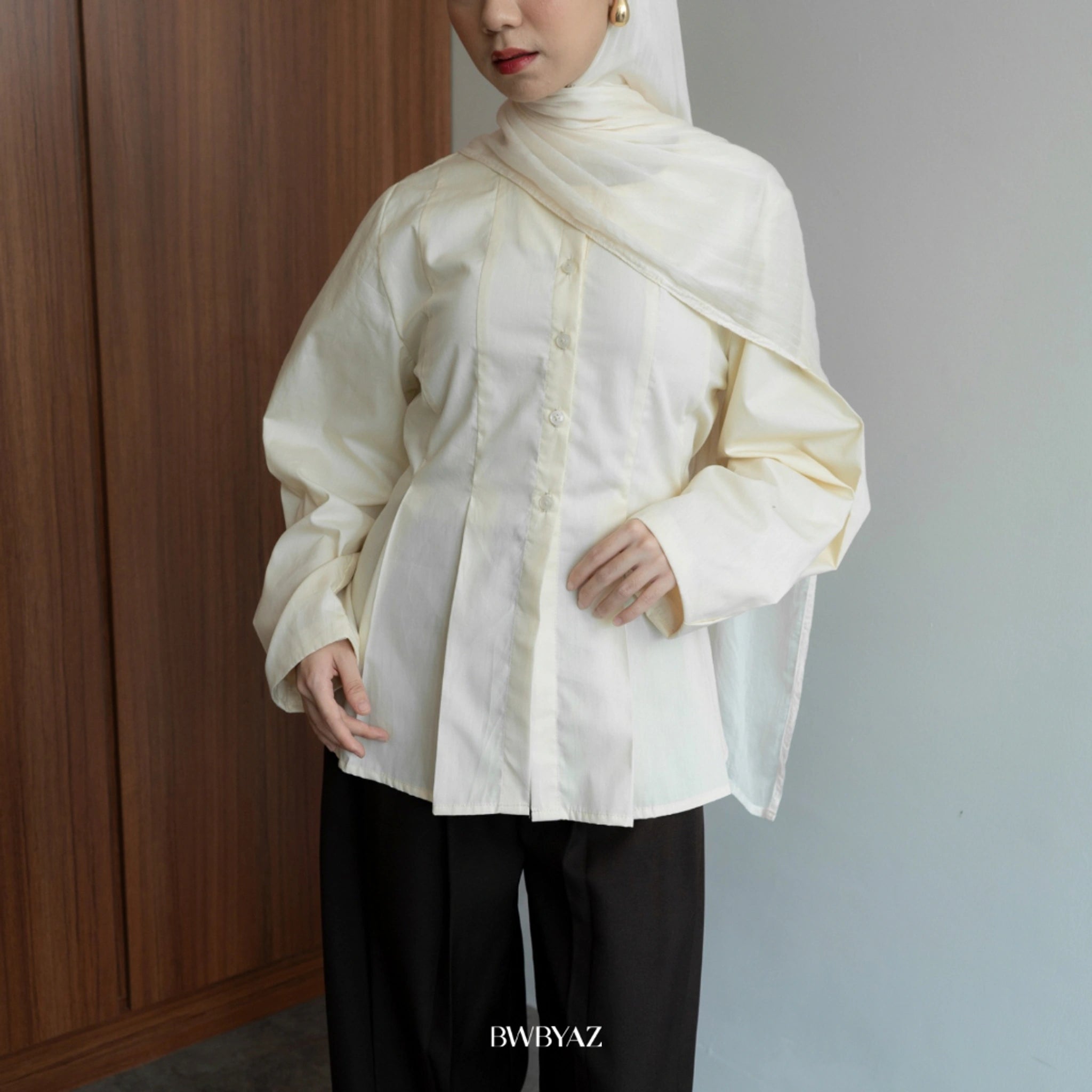 A person wearing a long sleeve butter cream peplum blouse with a round neckline from BWBYAZ and a denim skirt.