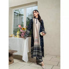 Woman in charcoal color patterned traditional outfit by Haidee Orlin standing in a room with a table and flowers.