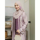 Woman wearing a purple patterned outfit by Haidee Orlin with a hijab in an indoor setting