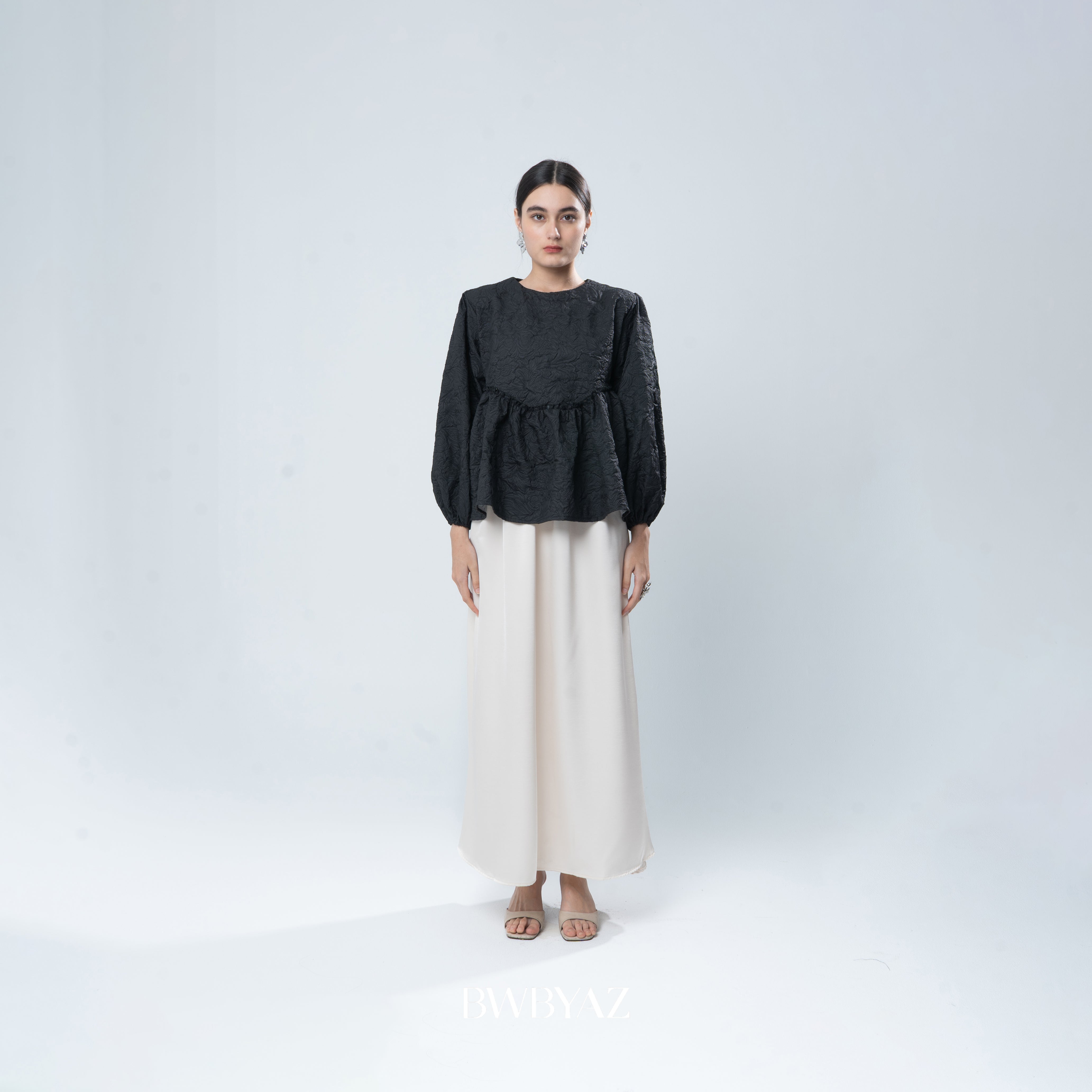 Woman wearing a black blouse by BWBYAZ and white skirt on a white background