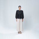 Woman wearing a black blouse by BWBYAZ and white skirt on a white background