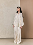 Woman wearing a white shirts with floral details by Studio Tui against a neutral background