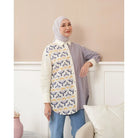 Woman wearing a patterned shirt by Abame in a room with a white wall and couch.