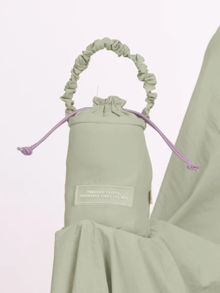 Light green drawstring bag from Muhajir Project with a label on a white background